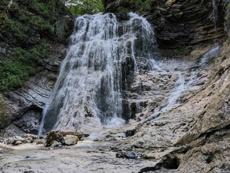 Der Stegovniški wasserfall in Slowenien mit grünem Wald und Felsen
